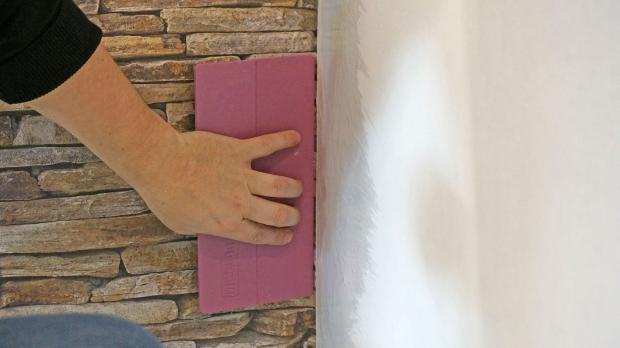 Tapete mit Tapezierspachtel in die Ecke drücken