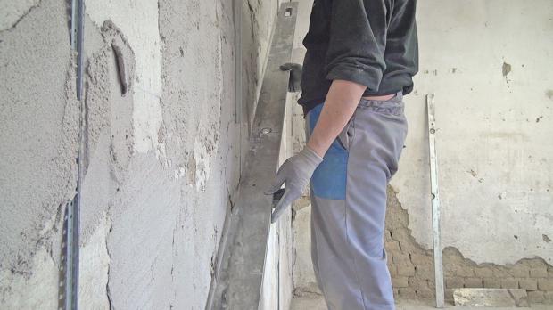 Verputzte Wand mit Richtscheit abziehen