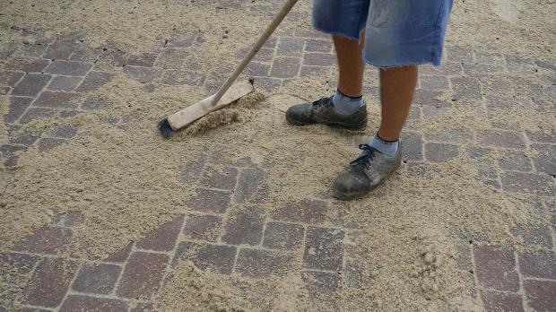 Sand in die Pflasterfugen einkehren